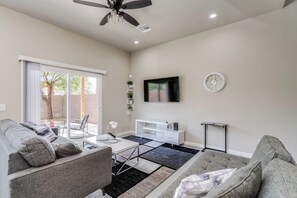 Un salon moderne avec un canapé, une table basse, un téléviseur et un ventilateur de plafond.