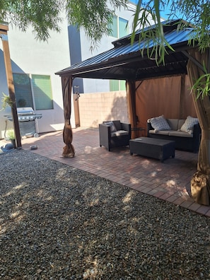 An outdoor patio area with a grill, seating, and a pergola. - Gather & Unwind | Patio | Ramada, BBQ | 3BR (Tucson)