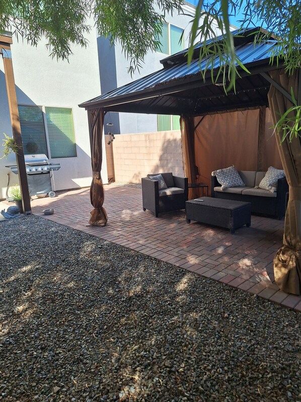 Un espace extérieur aménagé avec un barbecue, des sièges et une pergola.