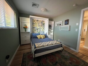 Ein Schlafzimmer mit einem Bett, einem Einbauschrank, einem Nachttisch und einem dekorativen Kopfteil.