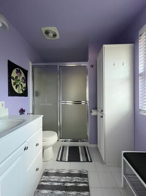 Ein Badezimmer mit Dusche, Toilette und einem weißen Schrank.