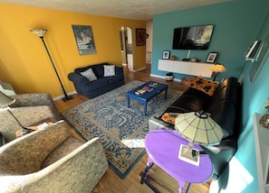 Ein Wohnzimmer mit einer Couch, einem Sessel, einem Couchtisch und einem Fernseher.