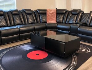 A black leather sectional sofa with a red vinyl record on a black table in front. - Cozy & Spacious 4-Bedroom Conyers Retreat with Gym (Conyers)