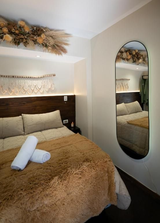 Una habitación de hotel con una cama grande, un espejo y un adorno en la pared.