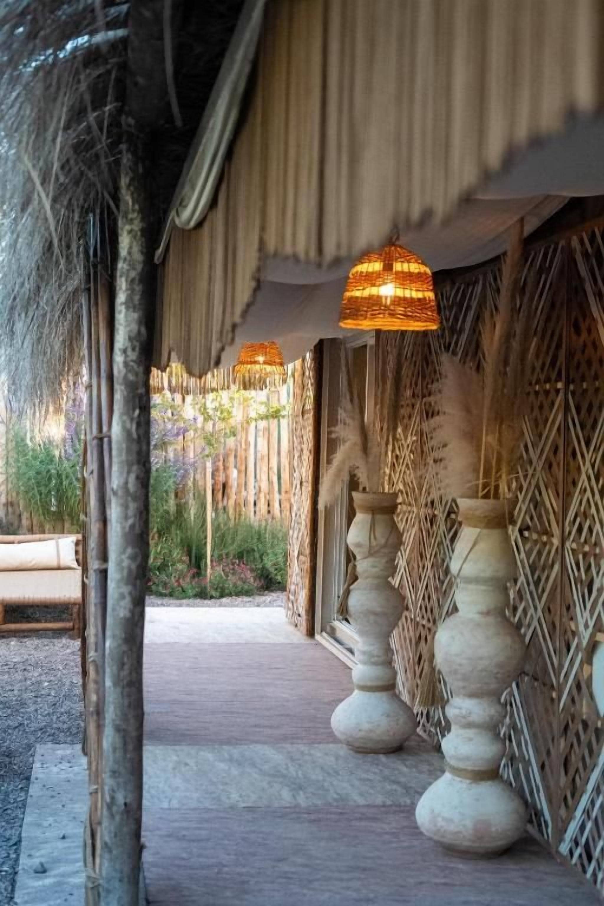 A pathway leading to a building with a thatched roof and a hanging light fixture.