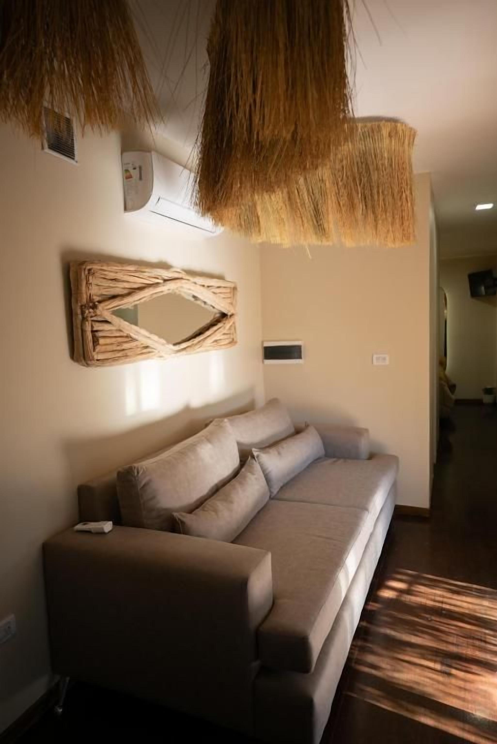 Una sala moderna con un sofá, un espejo decorativo y una lámpara colgante.