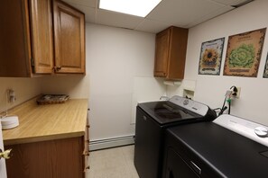 A laundry room with wooden cabinets, a washing machine, and a dryer. - Lakefront Retreat w/ Private Beach in Madison. Sleeps 12. (Madison)