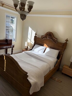 A traditional wooden bed with a headboard, a bedside table, a lamp, and a window with blinds. - Entire floor 4bed 3 bath conference table for 10 (San Rafael)