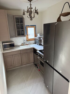 A kitchen with a stainless steel refrigerator, a microwave, a stove, and a chandelier. - Entire floor 4bed 3 bath conference table for 10 (San Rafael)