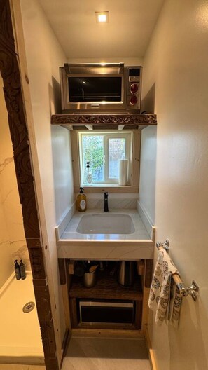 A compact kitchen with a built-in microwave, a window above the sink, and a towel rack. - Tiny home with gazebo (San Rafael)