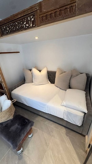 A modern bedroom with a sofa bed, a small wooden stool, and a woven basket. - Tiny home with gazebo (San Rafael)