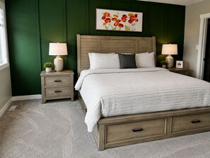 Een slaapkamer met een bed, twee nachtkastjes, een schilderij en een raam.