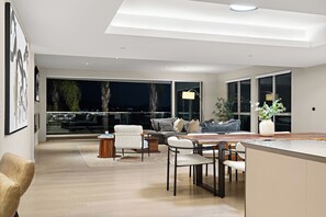Ein modernes Wohnzimmer mit Essbereich, großen Fenstern und Blick auf den Nachthimmel.
