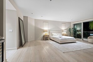 Ein modernes Schlafzimmer mit einem großen Bett, Nachttischlampen, einem großen Spiegel und einer Schiebeglastür zum Balkon.