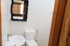 A small bathroom with a white sink, a toilet, and a mirror with a blue frame.