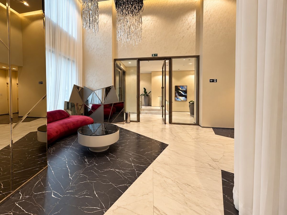 A modern lobby with a marble floor, a red sofa, a round table, and a chandelier.