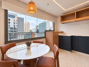 A modern kitchen with a large window, a round dining table, and built-in cabinets. - Cuidado em Cada Detalhe | Ao lado do Nubank Parque (São Paulo)
