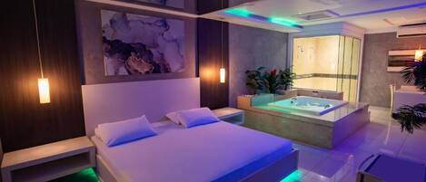 Un dormitorio moderno con una cama grande, una bañera integrada e iluminación ambiental.