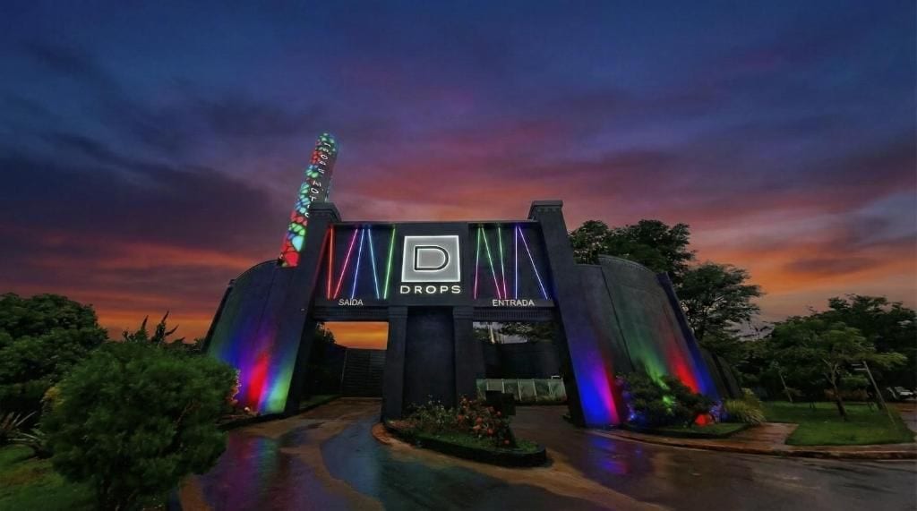 Um edifício com um amplo arco de entrada, uma placa com a inscrição 'DROPS' e uma exibição de luzes coloridas.