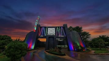 Um edifício com um amplo arco de entrada, uma placa com a inscrição 'DROPS' e uma exibição de luzes coloridas.