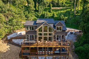Ein mehrstöckiges Haus mit Terrasse, umgeben von dichtem Wald.