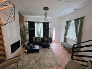 A modern living room with a sofa set, a coffee table, and a TV. There is a staircase leading to another level. - Perfect 3-bedroom house with AC in welcoming Houston neighborhood (Houston)