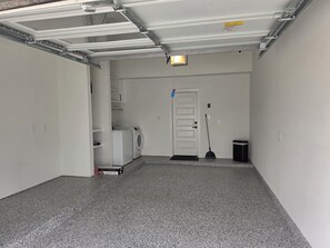 A clean, empty garage with a washing machine, a broom, and a trash bin. - Perfect 3-bedroom house with AC in welcoming Houston neighborhood (Houston)