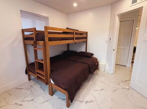A bunk bed with a ladder in a room with white walls and marble flooring. - Luxury Miami Stay • Near Wynwood/Design District (Miami)