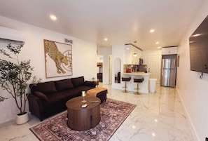 A modern living room with a sofa, coffee table, and a large potted plant. - Luxury Miami Stay • Near Wynwood/Design District (Miami)