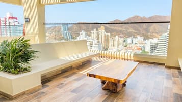 Ein Balkon mit einem Holztisch, einer Bank und einem Blumentopf.