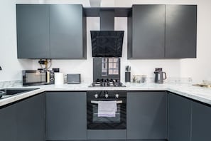 Eine moderne Küche mit dunklen Schränken, einem Gasherd, einer Mikrowelle und einer Kaffeemaschine.