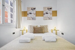 Ein Schlafzimmer mit einem Bett, zwei Nachttischen, einem Fenster und Kunstwerken an der Wand.