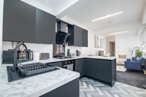 A modern kitchen with dark cabinets, a marble countertop, and a built-in stove. - The Vittoria | 2 BR | Wi-Fi | Workspace | Contractors/Leisure (Birmingham)