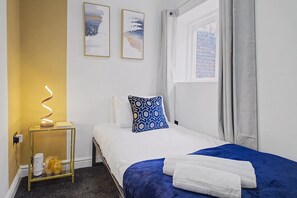 A hotel room with a bed, a bedside table with a lamp, a window with curtains, and two wall art pieces. - The Vittoria | 2 BR | Wi-Fi | Workspace | Contractors/Leisure (Birmingham)