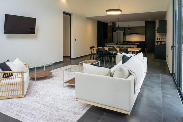 A modern living room with a sofa, a coffee table, and a TV mounted on the wall. - Xpuha Villa, Private Pool and Jungle, Near Beach (Xpu Ha)