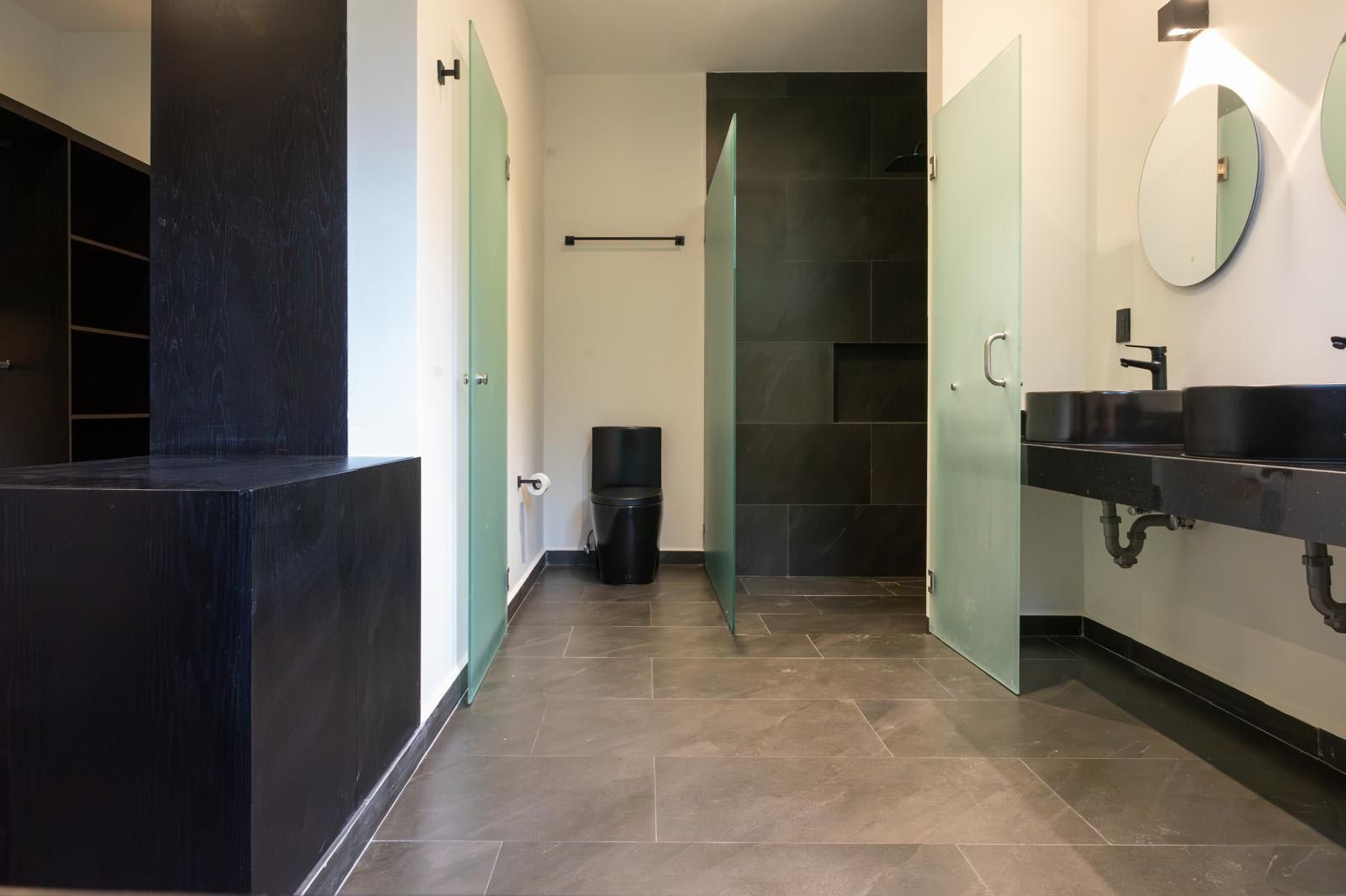 A modern bathroom with a black sink, a mirror, and a toilet.