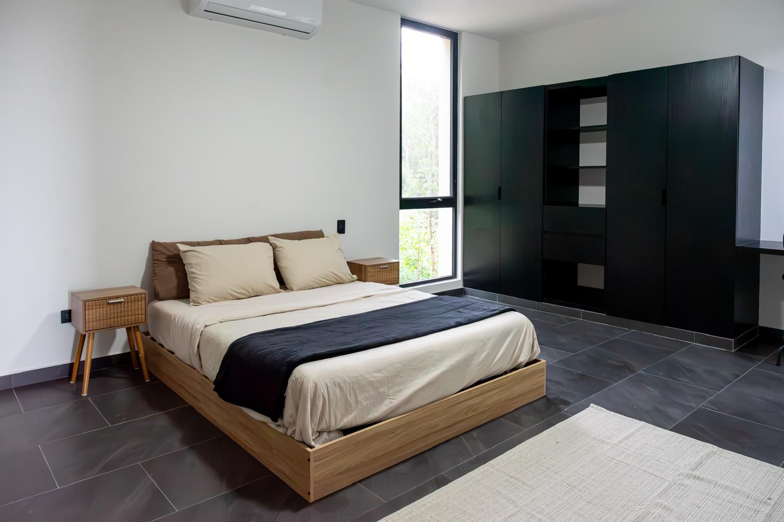 Une chambre moderne avec un lit, des tables de chevet, une armoire et une grande fenêtre.