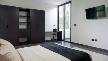 Une chambre à coucher moderne, équipée d’un lit, d’une armoire, d’un bureau et d’un téléviseur.