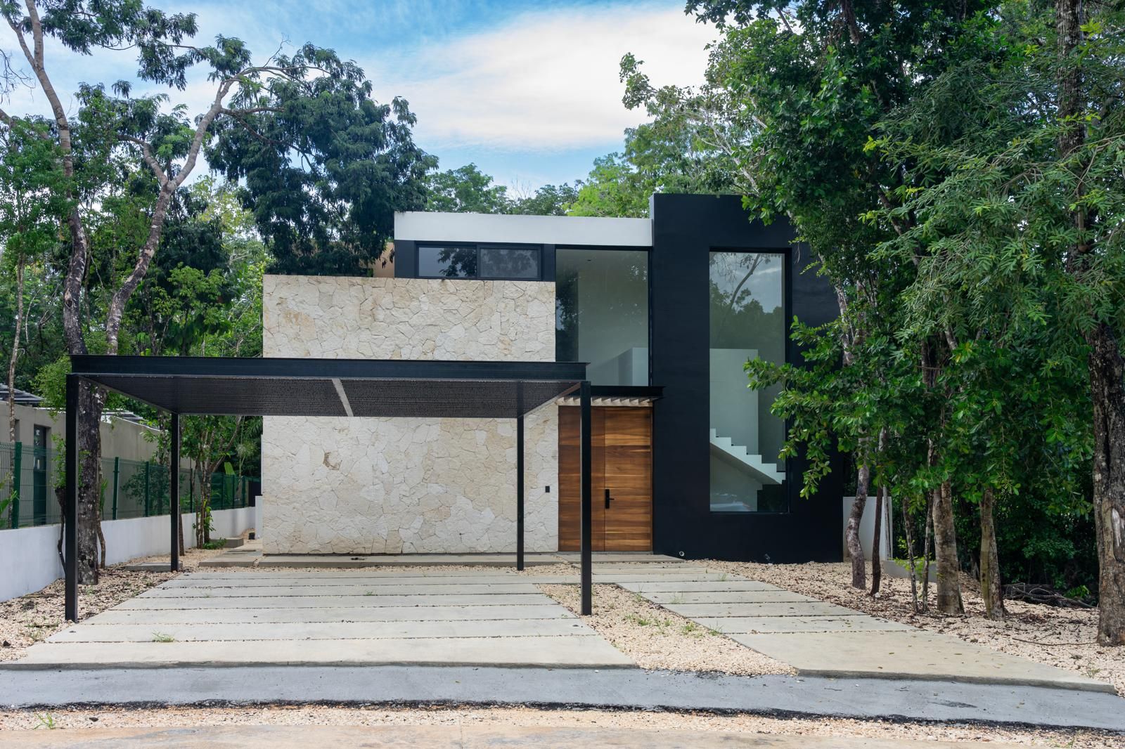 A modern house with a stone facade, a wooden door, and a covered patio area.