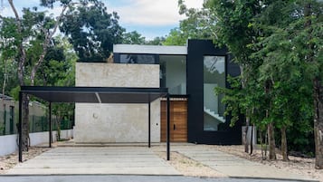 A modern house with a stone facade, a wooden door, and a covered patio area.