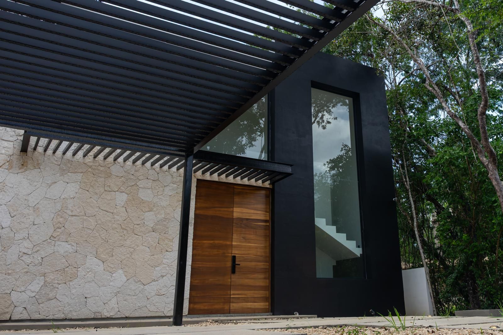 Un bâtiment moderne avec une façade en pierre, une porte en bois et une grande fenêtre en verre.
