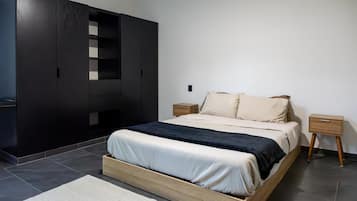 A modern bedroom with a bed, a wardrobe, and a nightstand.