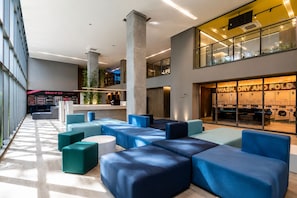 A modern lobby with seating areas, a reception desk, and a visible laundry facility. - On Paulista 1921 (Vila Mariana)