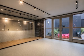 A modern bathroom with a glass shower enclosure, a wooden floor, and a view of the outside through large glass doors. - On Paulista 1921 (Vila Mariana)