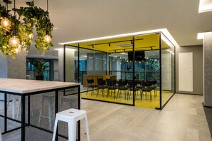 A modern office space with a glass partition, a bar area, and a seating arrangement. - On Paulista 1921 (Vila Mariana)