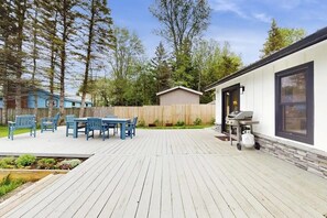 A wooden deck with a barbecue grill, outdoor furniture, and a stone wall. - Lakefront, dog-friendly house with amazing view, dock, 2 kayaks & canoe (Isle La Motte)