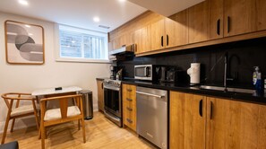 A modern kitchen with wooden cabinets, stainless steel appliances, and a dining area with a table and chairs.
