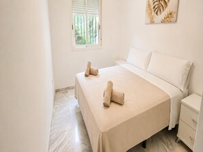 A hotel room with a bed, a nightstand, a window with blinds, and a wall decoration. - Apartment with private patio in Marbella (Marbella)