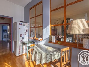 A kitchen with a dining table, chairs, a refrigerator, and a window with a view of bicycles. - Charming apartment in the heart of Angers (Angers)