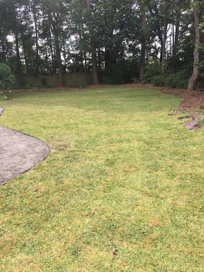 A grassy outdoor area with trees and a wooden fence. - Child-Friendly Retreat Near Charleston (Hanahan)